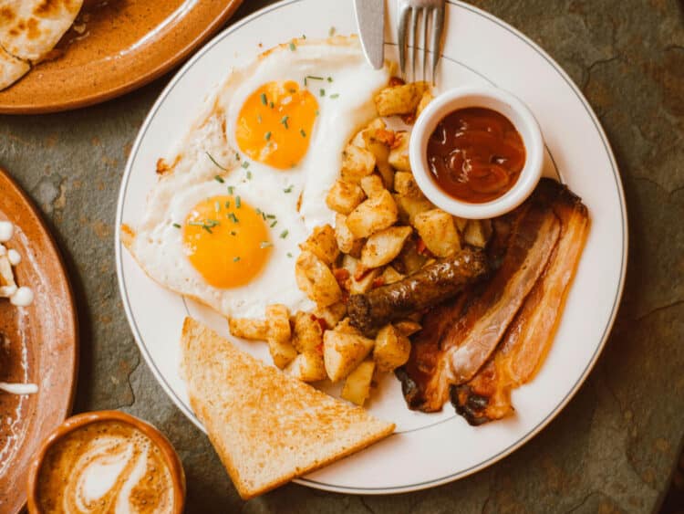 breakfast plate with eggs, potatoes and bacon with sauce and toast