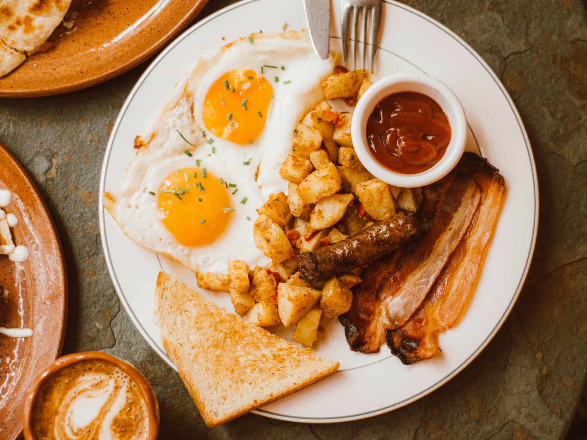breakfast plate with eggs, potatoes and bacon with sauce and toast