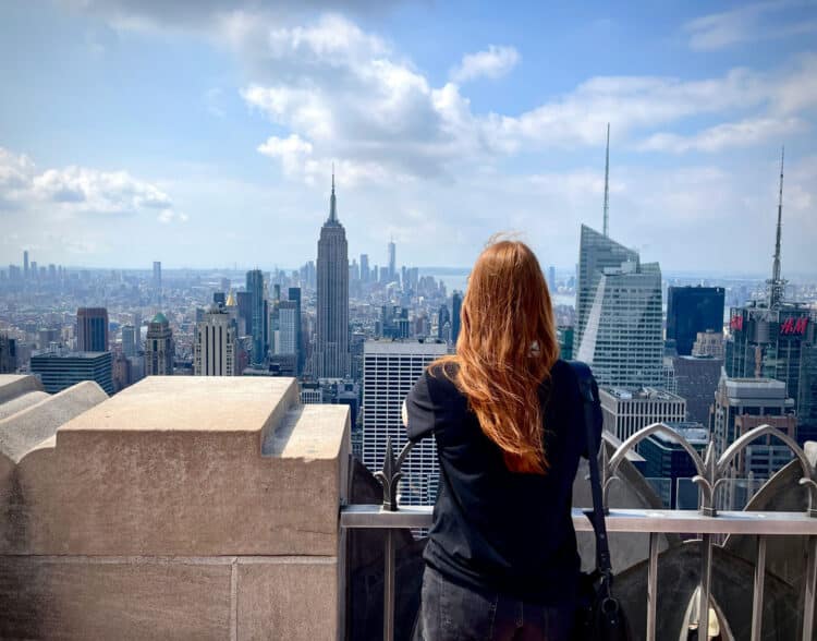 woman leaning out overlooking new york skyline and empire state building