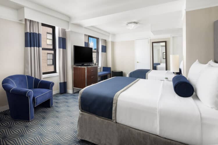 metro queen room with two large double windows, two large double beds and a full length mirror and blue armchair