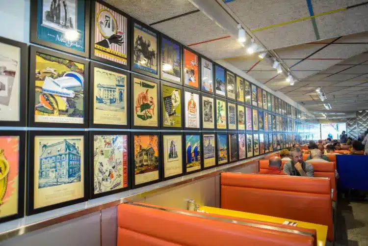 view of tick tock diner booths with different images and graphics on the walls in the form of paintings, orange booth seats and large mirrors