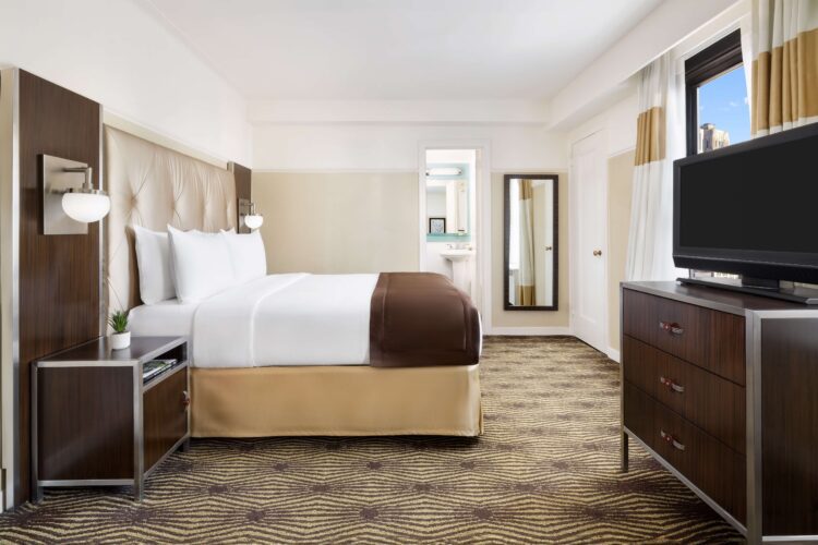 metro queen suite with large city view windows, television stand and full length mirror