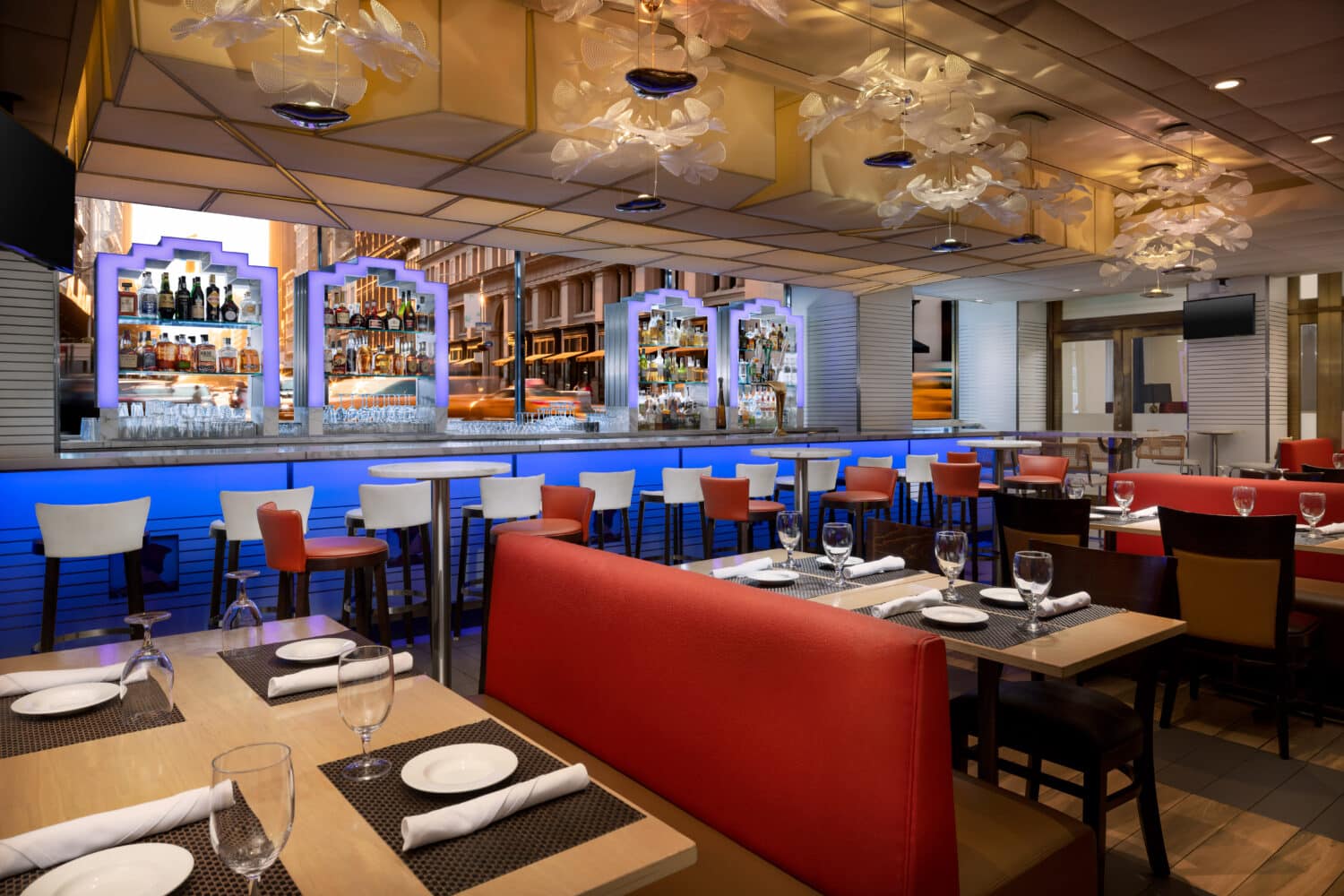 trattoria bar in nyc midtown with view of modern bar with spirits, dining place settings and large chairs