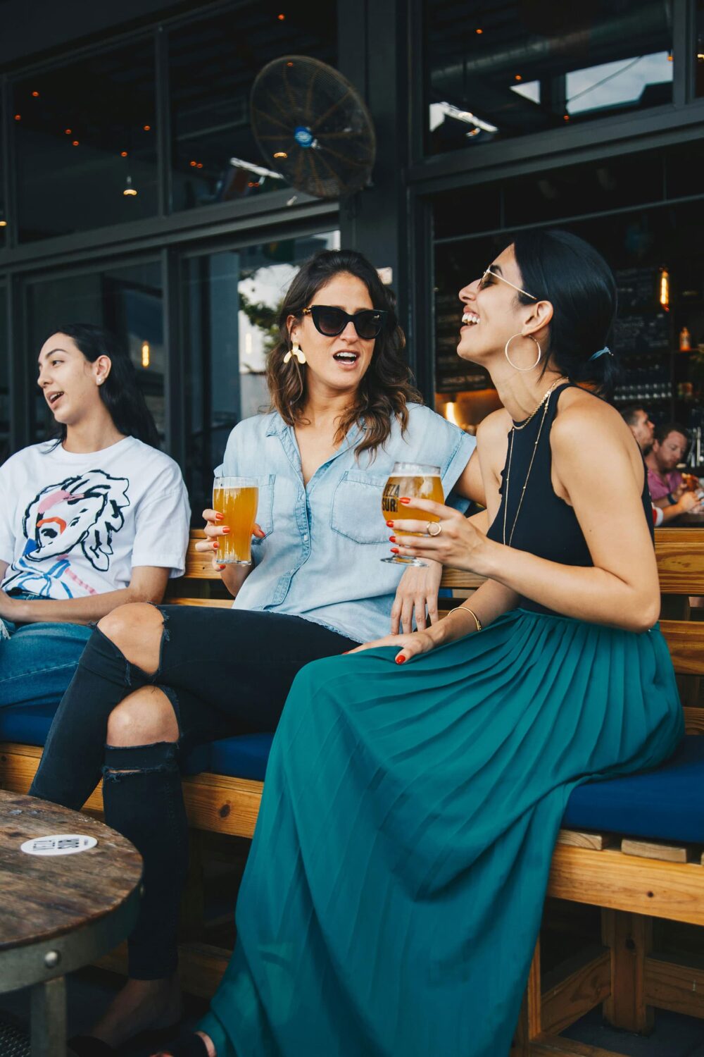 women laughing on sunny day drinking ale at public house