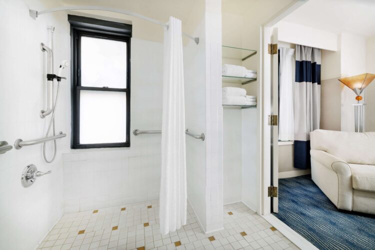 Accessible bathroom with roll-in shower, grab bars, curtain partition, and open shelving with towels