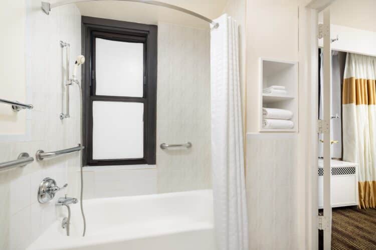ada tub at the new yorker nyc hotel with shower and shower curtain and window