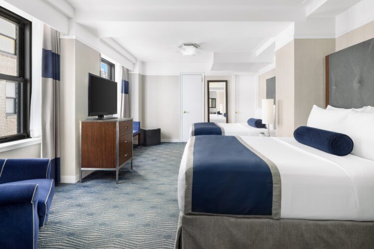 Accessible executive double room with two beds, blue accents, armchair seating, and workspace