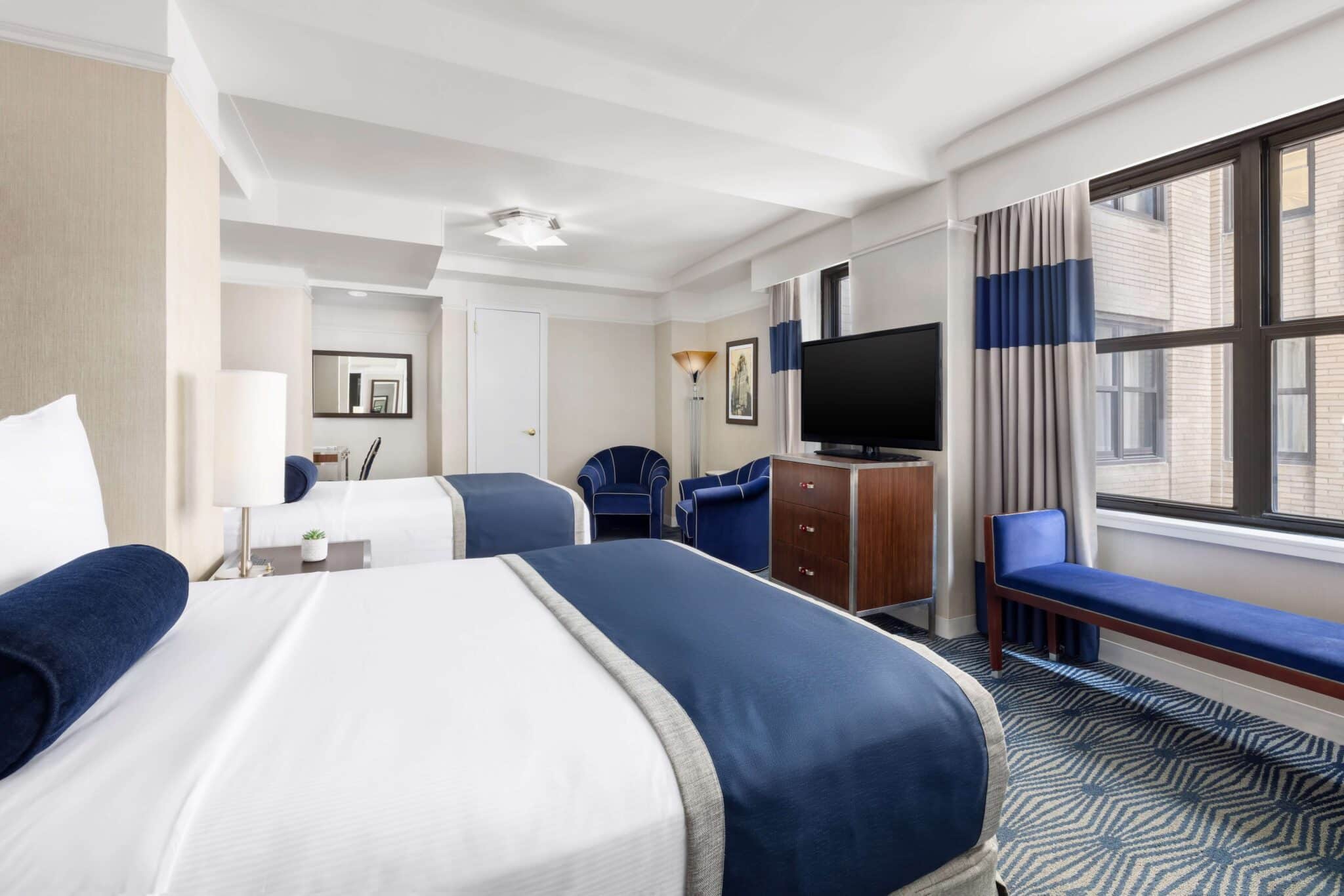 executive double room with double beds with window view of two large windows, television unit and large vanity mirror