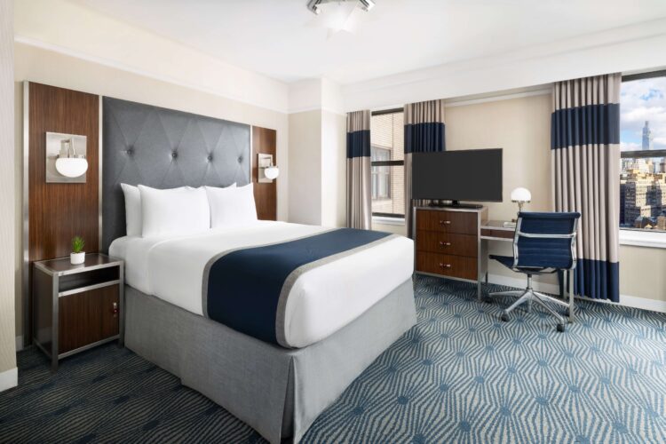 new yorker executive queen suite with window view of nyc, desk seating area and television set