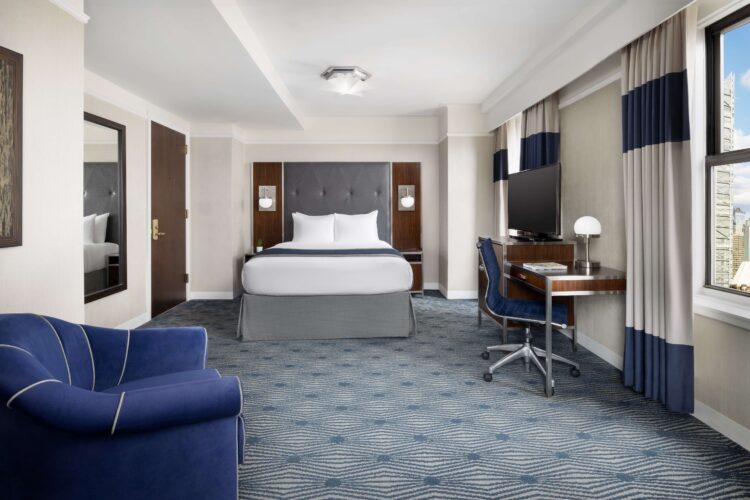 executive queen suite at the new yorker with large double windows, desk seating area and blue corner armchair