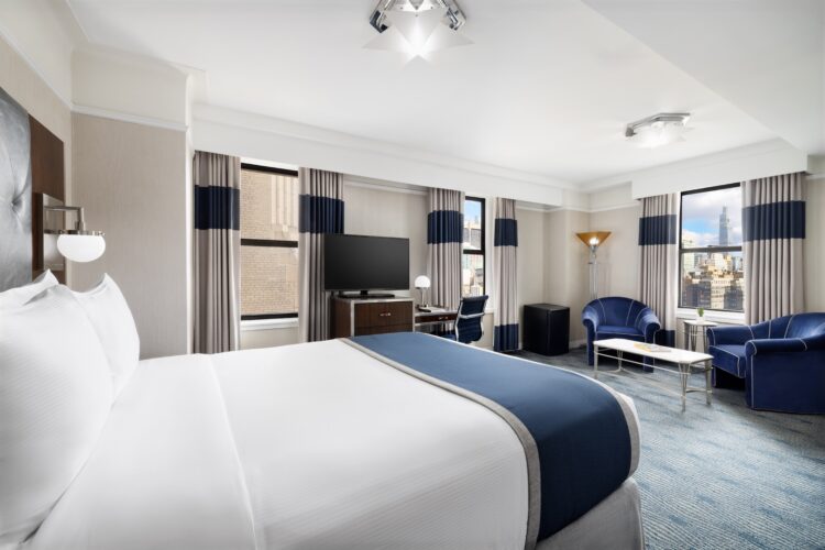 exec queen suite at the new yorker midtown nyc large spacious room with two armchairs, lamps and large window