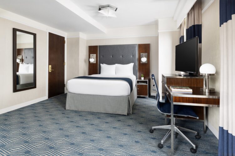 exec queen suite at the new yorker midtown nyc wth large double bed, blue decor and desk for work station