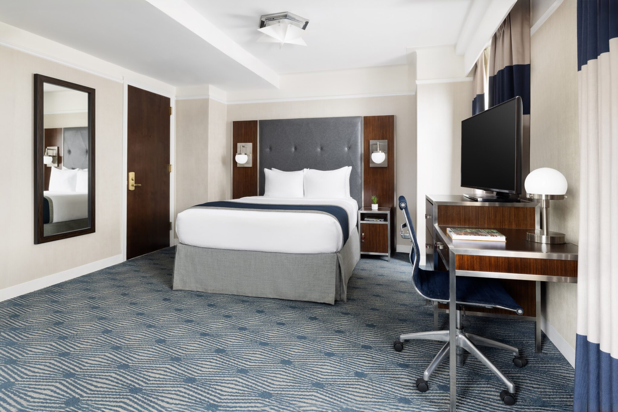 exec queen suite at the new yorker midtown nyc wth large double bed, blue decor and desk for work station