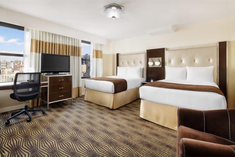 hotel queen suite at the new yorker with double beds, large television set and desk seating area