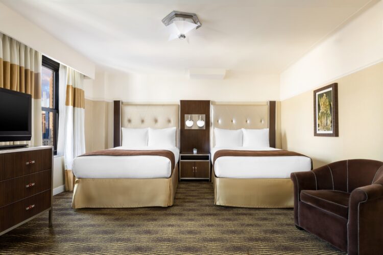 hotel queen suite at the new yorker with twin beds large brown armchair and window