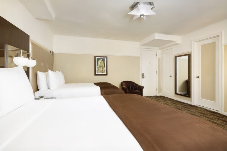 hotel queen suite at the new yorker twin bed rooms with large double mirror and arm chair