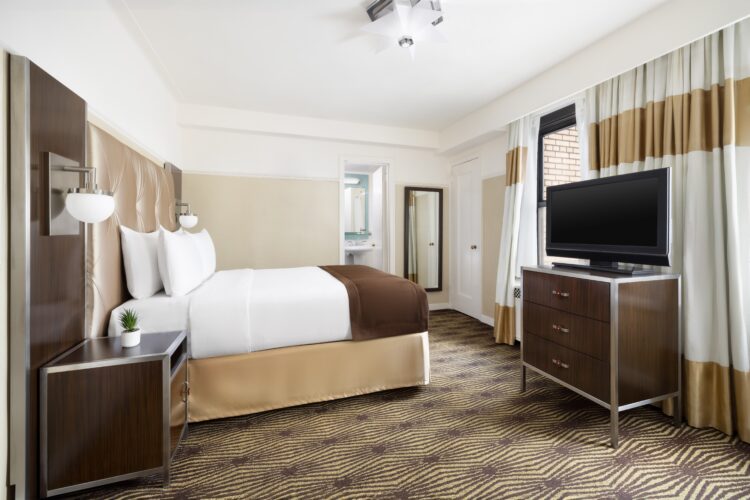 hotel queen suite at the new yorker with large television, beige design and double bed