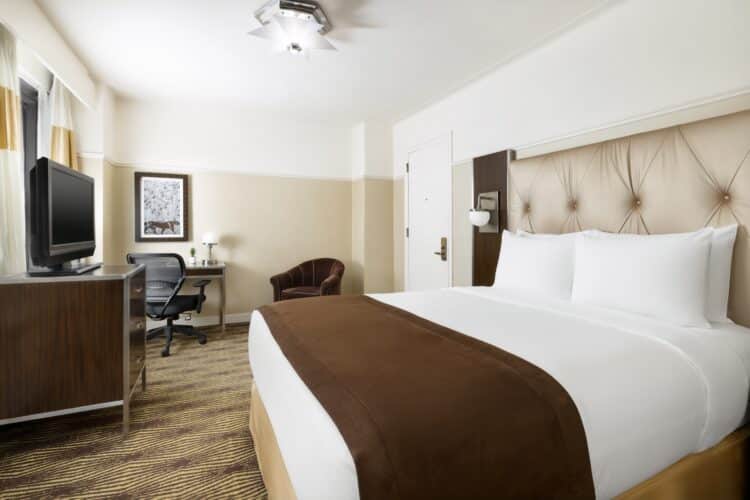 hotel queen suite at the new yorker with large double bed and view of armchair and wall art