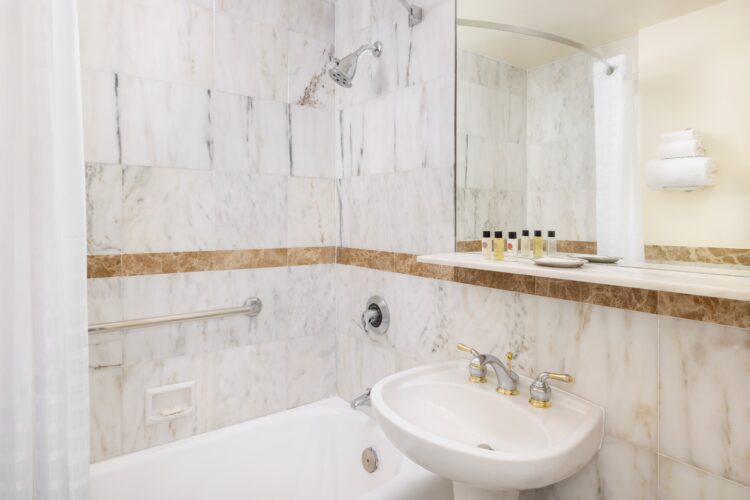 Marble bathroom with bathtub, shower, and pedestal sink in premium hotel suite