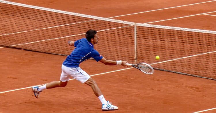 US tennis open - man serving tennis ball on orange pitch
